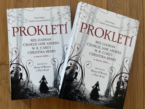 photograph showing two copies of the Czech translation of Cursed, edited by Marie O'Regan and Paul Kane, on a wooden background