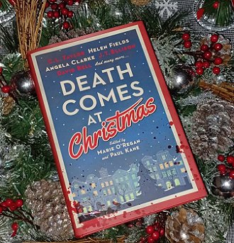 photograph of a copy of Death Comrs at Christmas, edited by Marie O'Regan and Paul Kane, lying on a bed of pine branches, red berries, golden pinecones and baubles