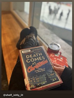 photograph of a person sitting with their legs up on a wooden bench inside a window, with a copy of Death Comes at Christmas, edited by Marie O'Regan and Paul Kane, on their lap. 