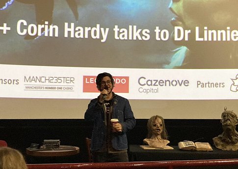 Corin Hardy speaking about the Hallow, with two monster heads and a copy of The Book of  Illusions