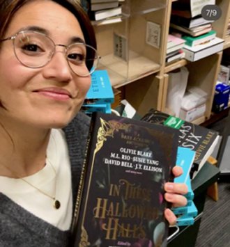 photograph of author Olivie Blake holding a copy of In These Hallowed Halls, edited by Marie O'Regan and Paul Kane.