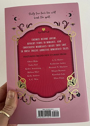 photo of a man's hand holding up a copy of The Secret Romantic's Book of Magic, edited by Marie O'Regan and Paul Kane, to show the back cover
